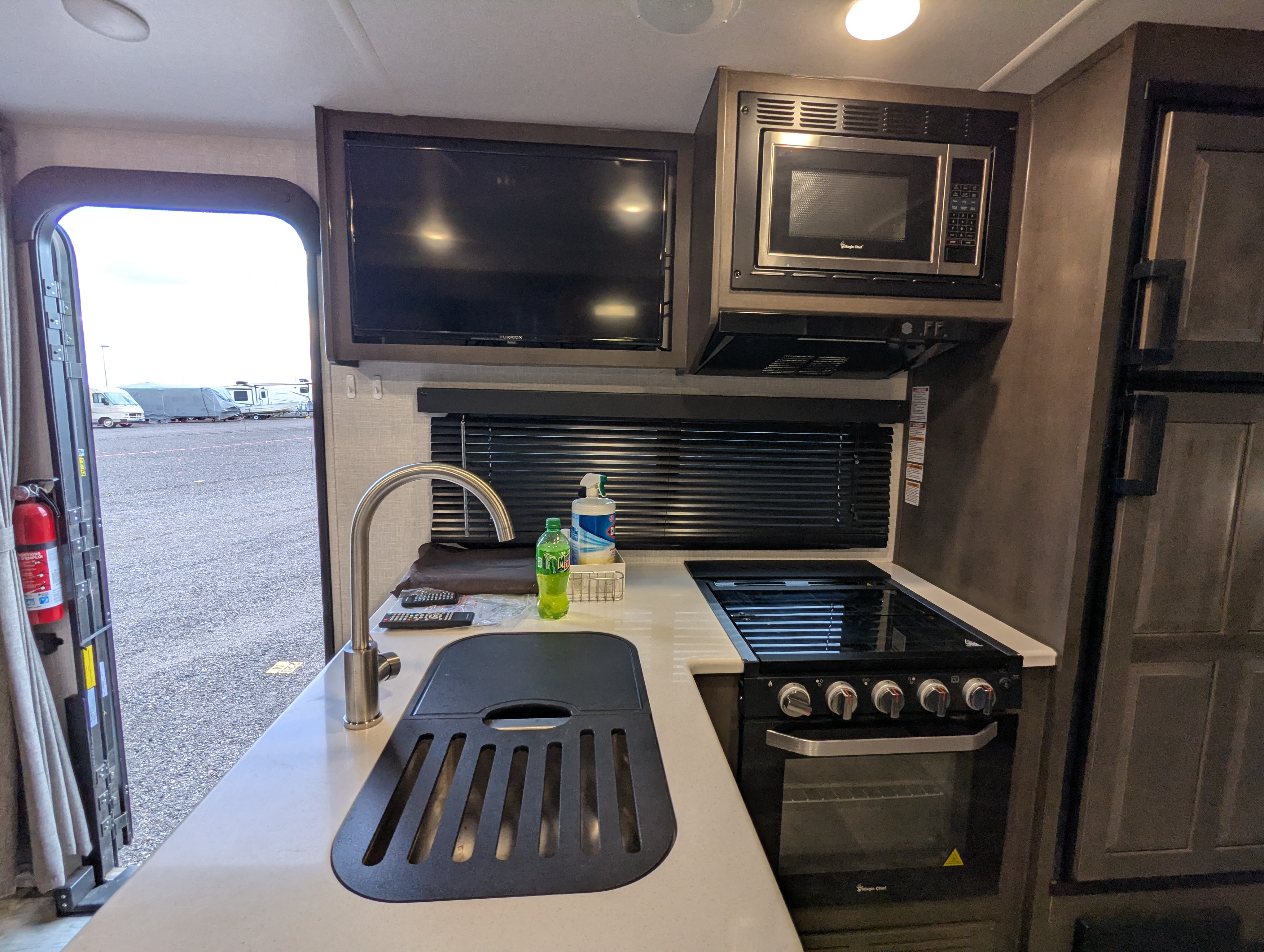 Kitchen — sink, TV, microwave, and stove with door open